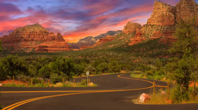 Winding scenic road into Sedona Arizona with red rock buttes glowing at sunset