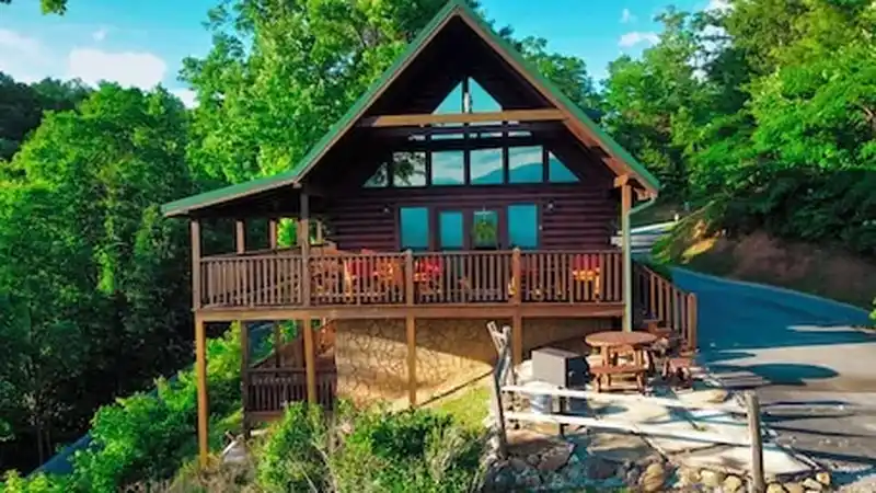 A log cabin with a deck and rocking chairs on a wooded ridge above Gatlinburg, Tennessee.